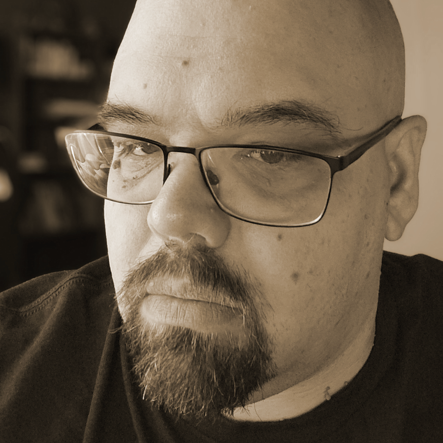 Black and white portrait of a bald man wearing glasses.